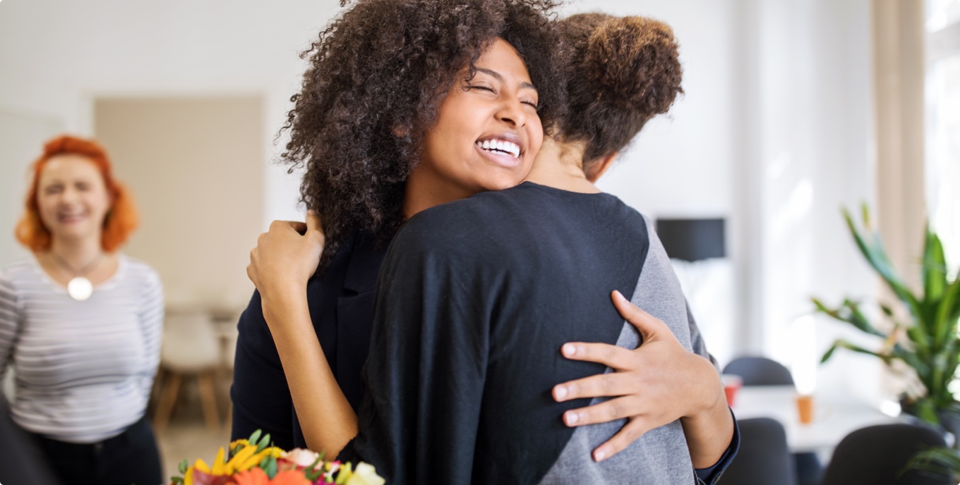 Duas pessoas a abraçarem-se e a sorrirem